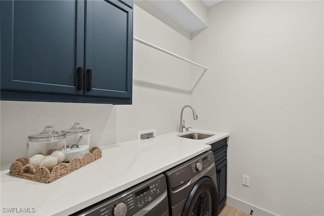 washroom with light wood-type flooring, a sink, cabinet space, baseboards, and washing machine and clothes dryer