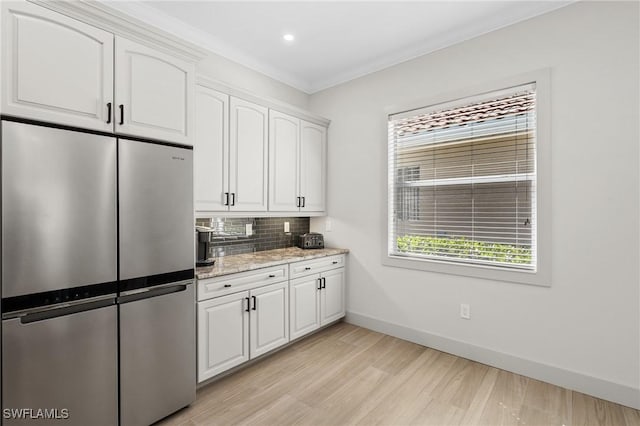 kitchen featuring white cabinetry, freestanding refrigerator, light wood-style floors, decorative backsplash, and baseboards