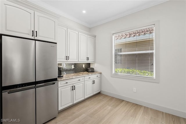 kitchen with tasteful backsplash, baseboards, freestanding refrigerator, light wood-style floors, and white cabinets