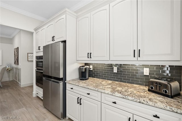 kitchen with decorative backsplash, crown molding, white cabinets, and stainless steel appliances