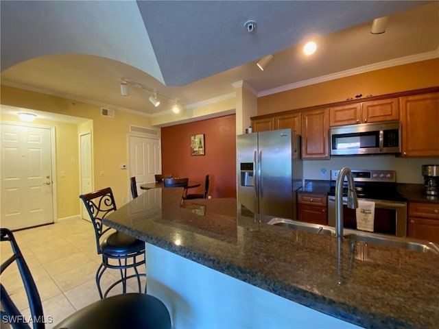 kitchen with stainless steel appliances, brown cabinetry, crown molding, and light tile patterned floors