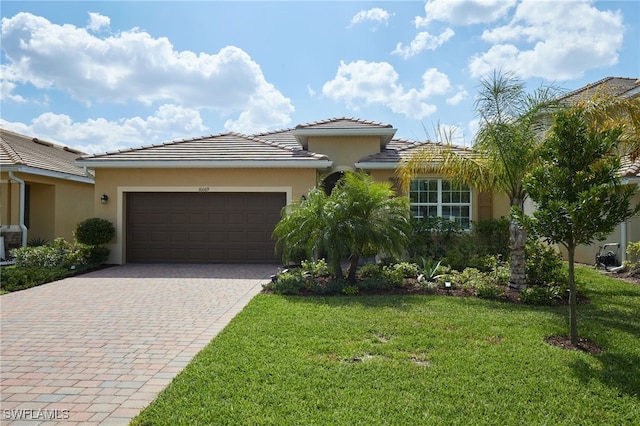 view of front facade featuring a garage, a tiled roof, decorative driveway, a front lawn, and stucco siding