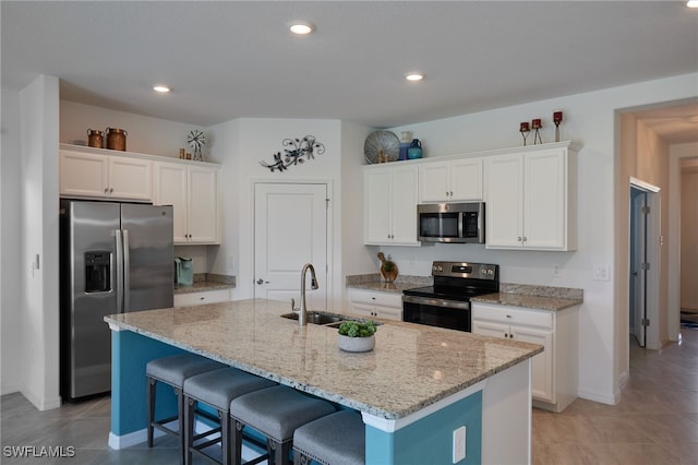 kitchen featuring appliances with stainless steel finishes, white cabinetry, a sink, and a breakfast bar area