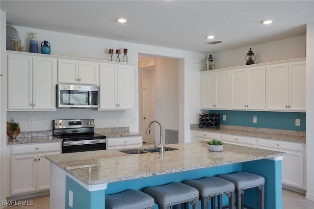 kitchen featuring white cabinets, stainless steel appliances, a sink, and a kitchen breakfast bar