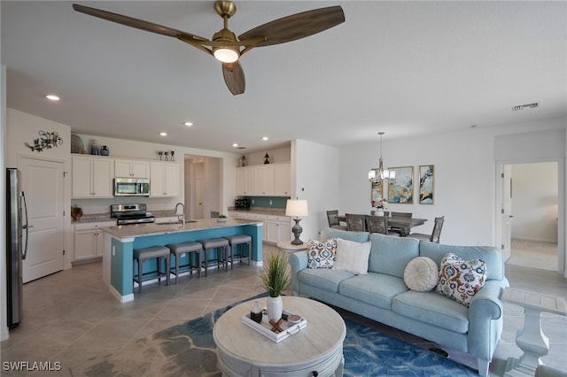 tiled living area with ceiling fan with notable chandelier, a sink, visible vents, and recessed lighting