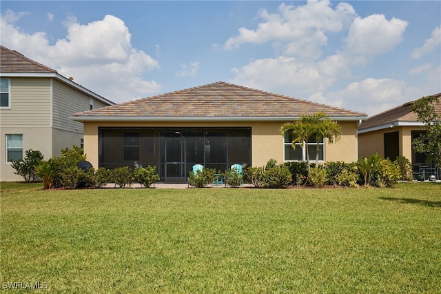 rear view of house featuring a sunroom, a lawn, and stucco siding