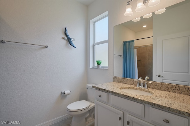 bathroom with toilet, a shower with curtain, baseboards, and vanity