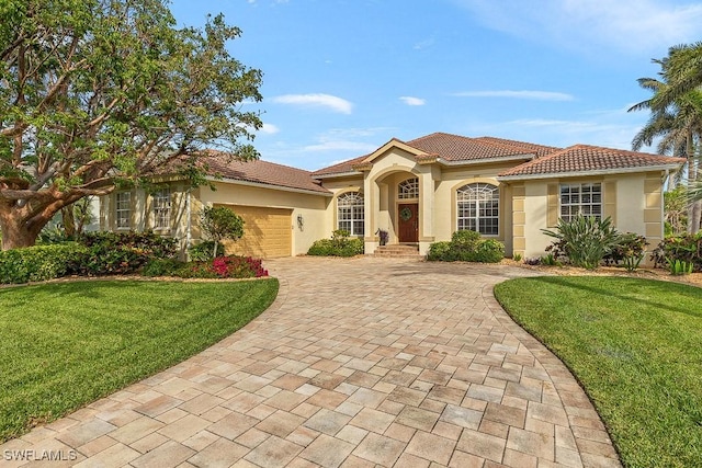 mediterranean / spanish house with decorative driveway, an attached garage, a front lawn, and stucco siding