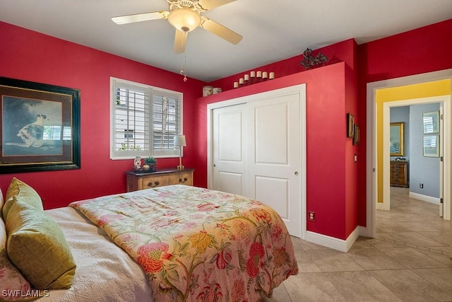 bedroom featuring light tile patterned floors, a closet, a ceiling fan, and baseboards