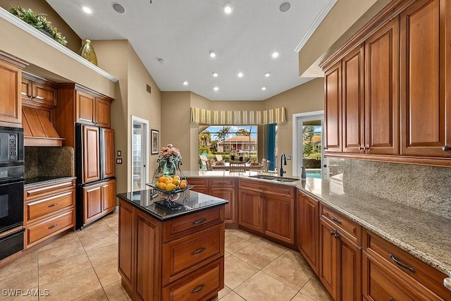 kitchen with tasteful backsplash, dark stone counters, brown cabinets, black appliances, and a sink