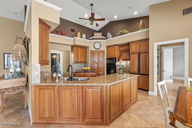 kitchen featuring brown cabinetry, a sink, light stone countertops, a peninsula, and black appliances