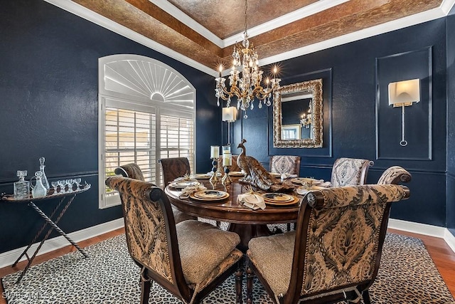 dining area with baseboards, crown molding, a chandelier, and wood finished floors