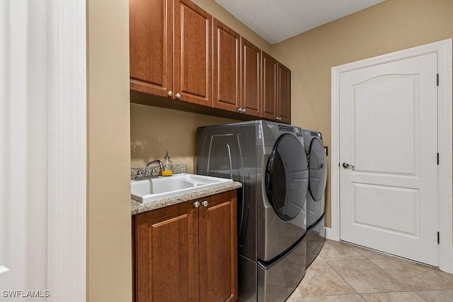 laundry room featuring independent washer and dryer, cabinet space, a sink, and light tile patterned floors