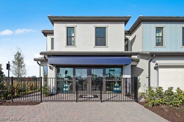 view of front facade with a garage, fence, and stucco siding