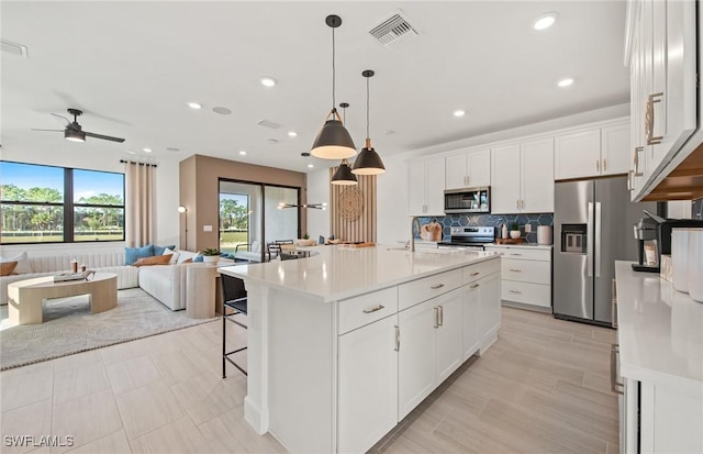 kitchen featuring visible vents, white cabinetry, open floor plan, appliances with stainless steel finishes, and backsplash