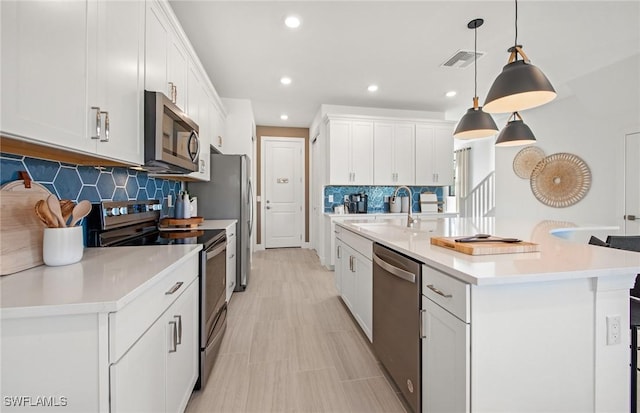 kitchen featuring stainless steel appliances, visible vents, a sink, and white cabinetry