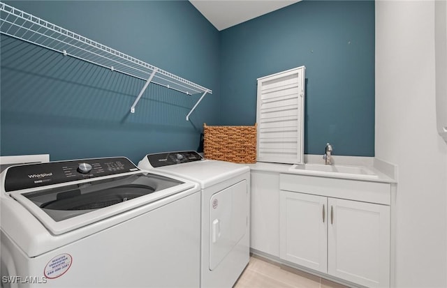 laundry area with light tile patterned floors, cabinet space, washer and dryer, and a sink