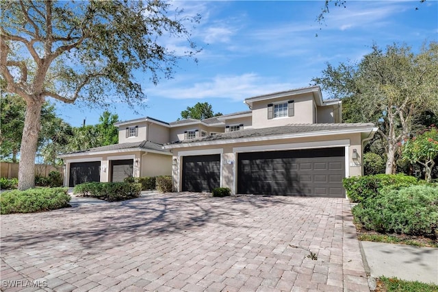 prairie-style house with stucco siding, an attached garage, and decorative driveway