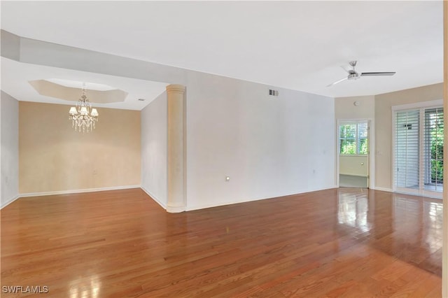 unfurnished room featuring visible vents, baseboards, a tray ceiling, ceiling fan with notable chandelier, and light wood-type flooring