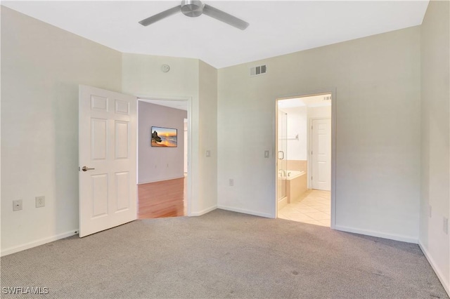 unfurnished bedroom featuring ensuite bath, light colored carpet, visible vents, and baseboards