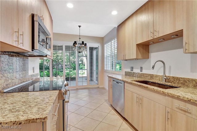 kitchen featuring light stone countertops, appliances with stainless steel finishes, light brown cabinetry, and a sink