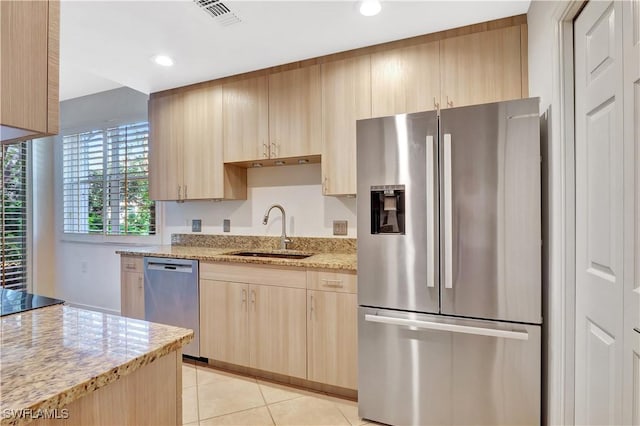 kitchen featuring light brown cabinets, a sink, light stone counters, stainless steel appliances, and light tile patterned flooring