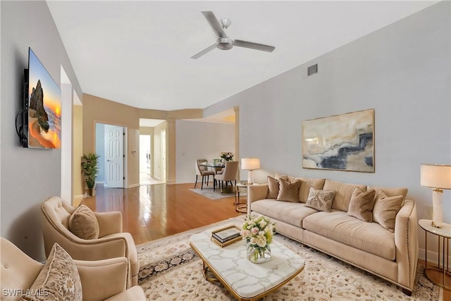 living room with ceiling fan, visible vents, baseboards, and wood finished floors