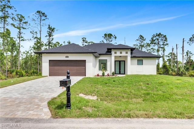 prairie-style home featuring a front lawn, decorative driveway, an attached garage, and stucco siding