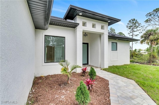 entrance to property featuring a lawn and stucco siding