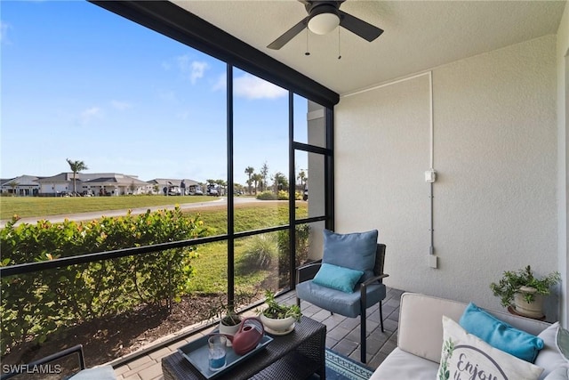 sunroom / solarium featuring a residential view and a ceiling fan