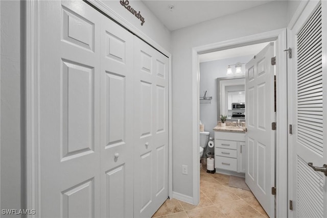 bathroom featuring toilet, a closet, vanity, and tile patterned floors