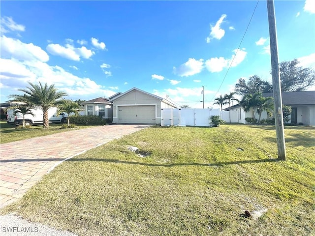 ranch-style home featuring decorative driveway, an attached garage, a front lawn, and fence