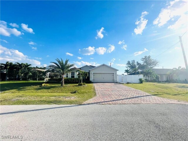view of front of home featuring a front lawn, fence, an attached garage, and decorative driveway