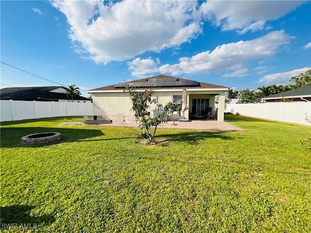 rear view of house featuring a fenced backyard, a fire pit, a lawn, stucco siding, and a patio area