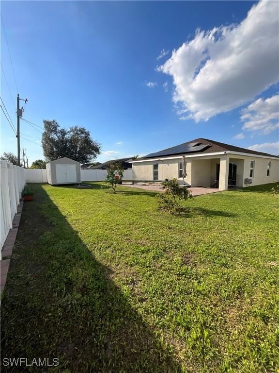 view of yard featuring an outbuilding, a fenced backyard, a patio, and a storage unit