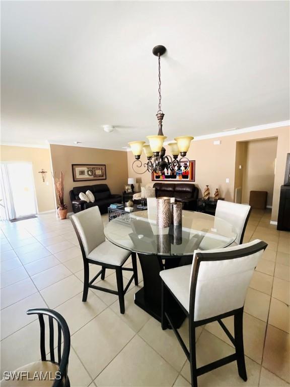 dining area with light tile patterned floors, ornamental molding, and a notable chandelier