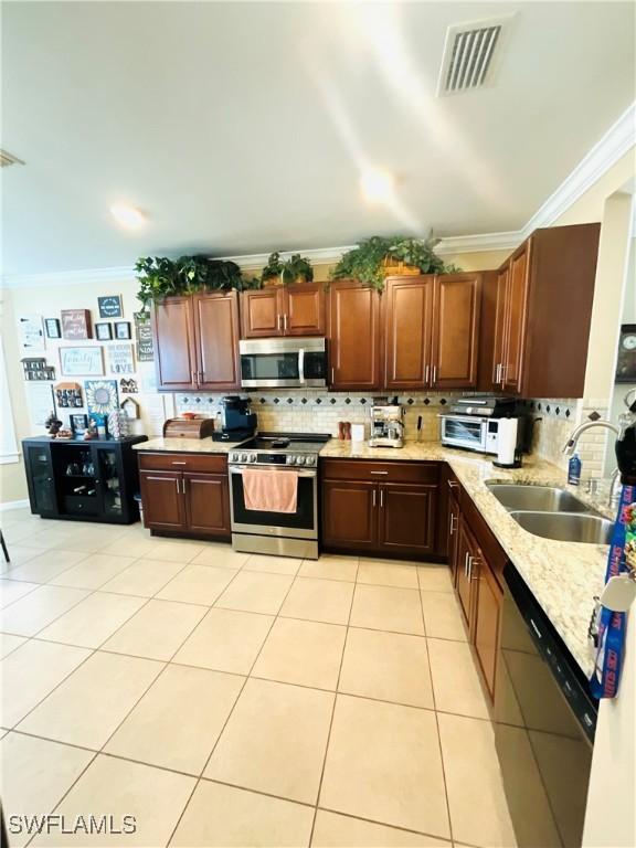 kitchen featuring visible vents, ornamental molding, stainless steel appliances, a sink, and light tile patterned flooring