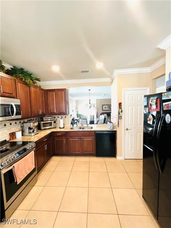 kitchen featuring light countertops, crown molding, black appliances, a sink, and light tile patterned flooring