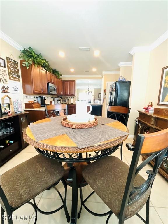 dining area with light tile patterned flooring, recessed lighting, visible vents, ornamental molding, and an inviting chandelier