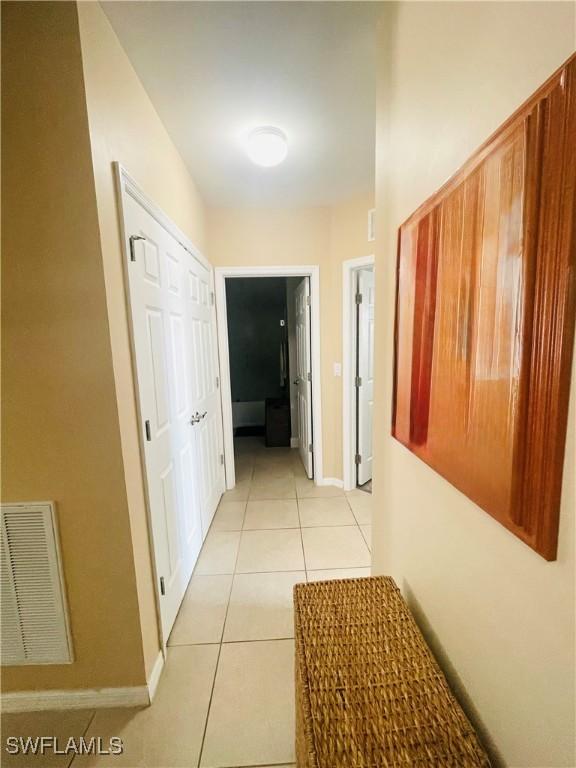 hallway featuring light tile patterned flooring, visible vents, and baseboards