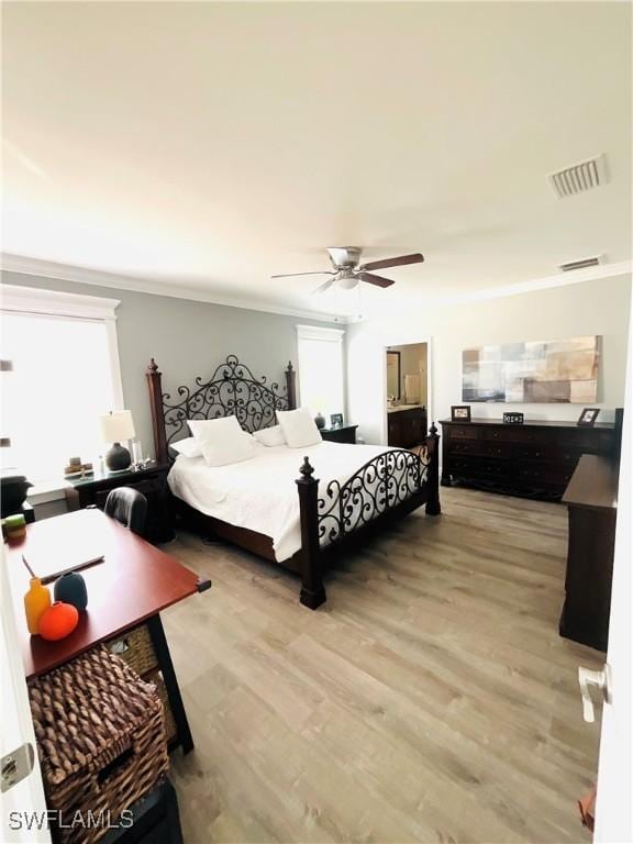 bedroom with multiple windows, light wood-type flooring, visible vents, and crown molding