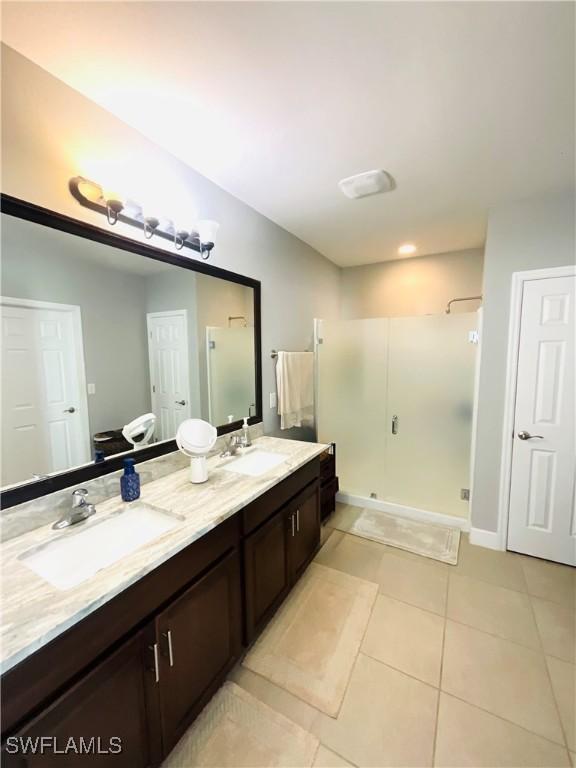 full bathroom featuring double vanity, tile patterned flooring, a sink, and a shower stall