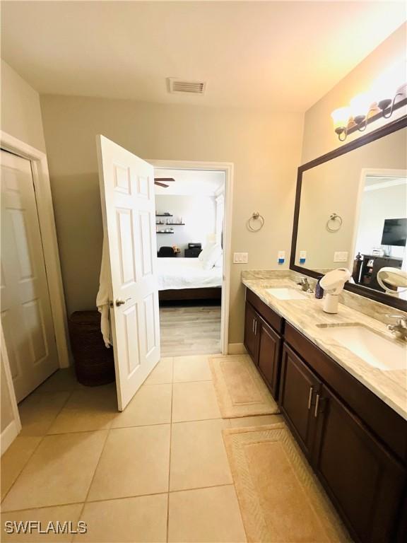 full bathroom featuring a sink, double vanity, connected bathroom, and tile patterned floors