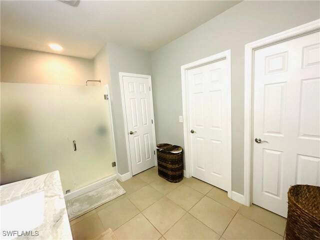 bathroom featuring baseboards, a stall shower, and tile patterned floors