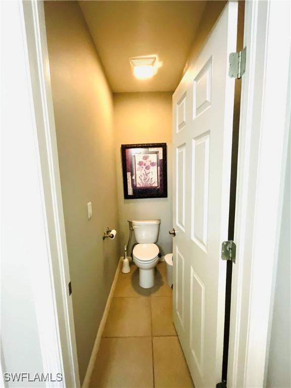 bathroom with tile patterned flooring, baseboards, and toilet