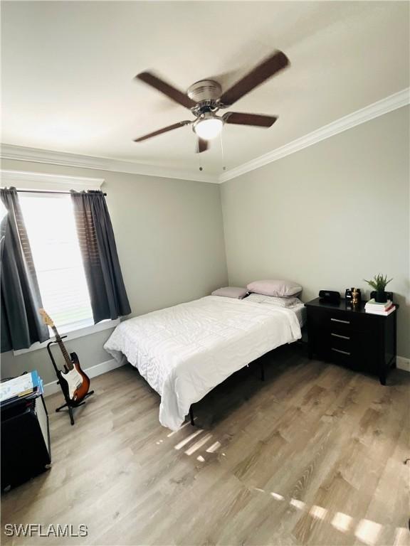 bedroom with light wood-type flooring, baseboards, and ornamental molding