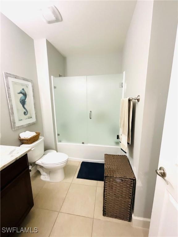 bathroom with vanity, combined bath / shower with glass door, tile patterned flooring, and toilet