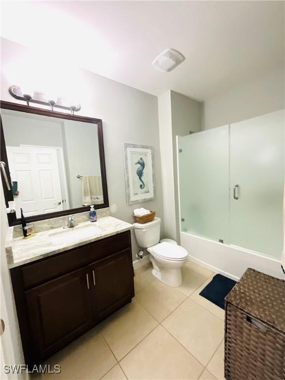 bathroom featuring tile patterned flooring, vanity, toilet, and bath / shower combo with glass door