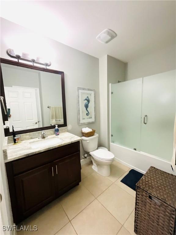 full bath with bath / shower combo with glass door, vanity, toilet, and tile patterned floors