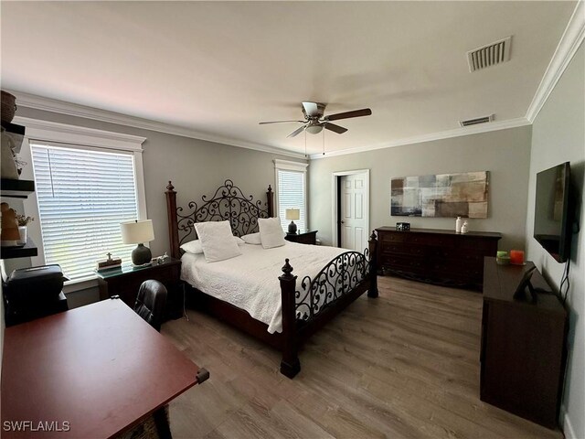 bedroom with visible vents, ceiling fan, crown molding, and wood finished floors